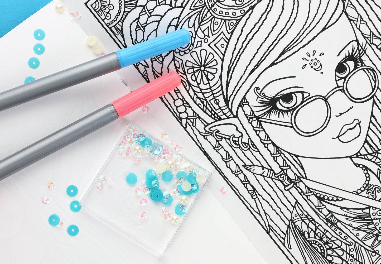 Detailed coloring page from the Be Yourself Coloring Book—24 Designs by Myka Jelina (Leisure Arts), featuring a girl with glasses, blue and pink markers, and scattered blue/white sequins on a white surface.