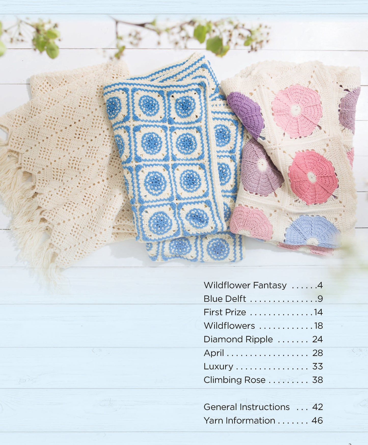 Three Crochet Spring Afghans by Leisure Arts—cream, blue and white, and pink with purple circles—are displayed on a light wooden surface for stylish home decor. A contents list is shown on the right.