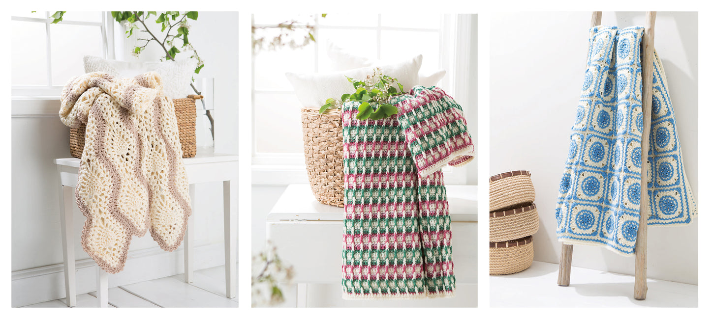 Three "Crochet Spring Afghans" by Leisure Arts are shown: a cream and tan scalloped blanket on a chair, a pink and green checkered one on a basket, and a blue and white geometric afghan hanging from a wooden ladder.