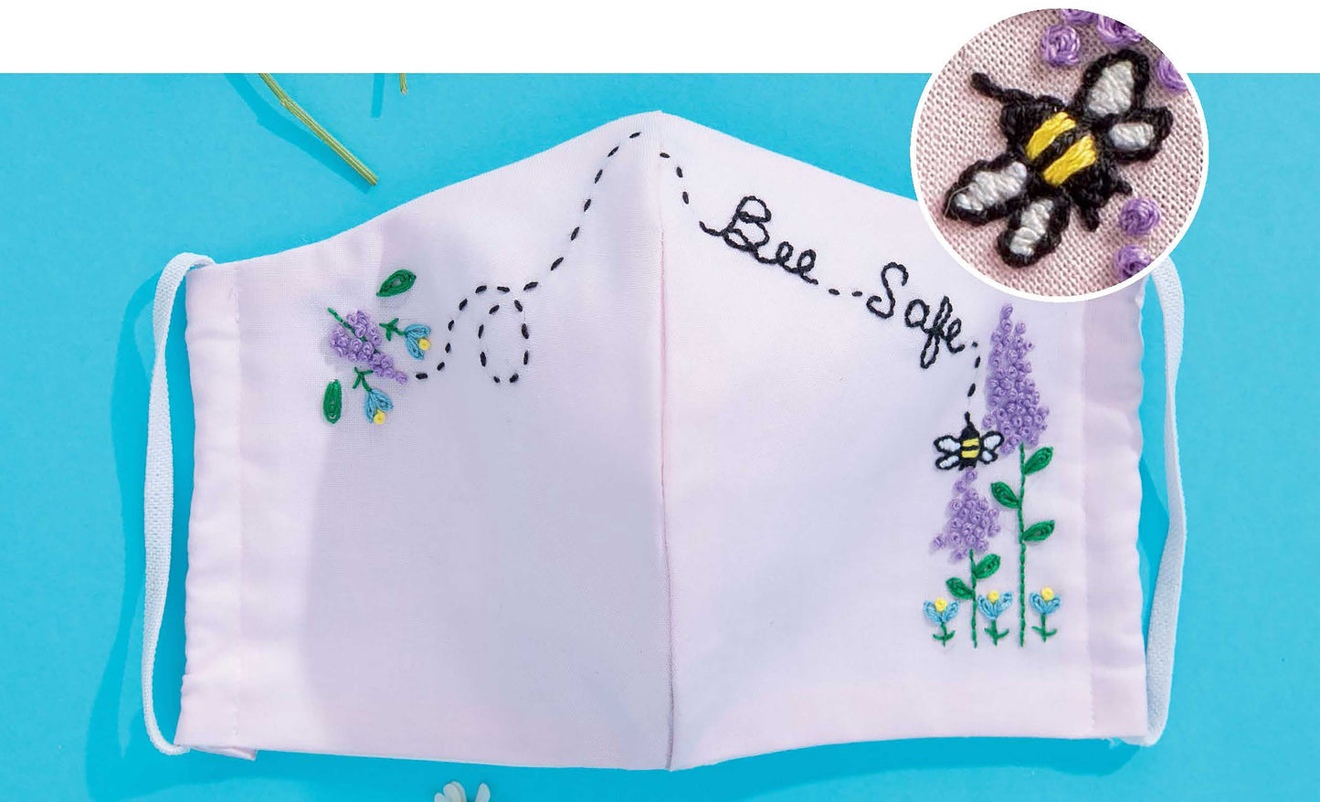 Leisure Arts’ Breathe Easy 2—30 Embellishments for Adding Style to Any Mask features creative ideas like a white fabric face mask with embroidered flowers, a bee, and “Bee Safe” for stylish, personalized masks. Close-up shows detailed bee embroidery.