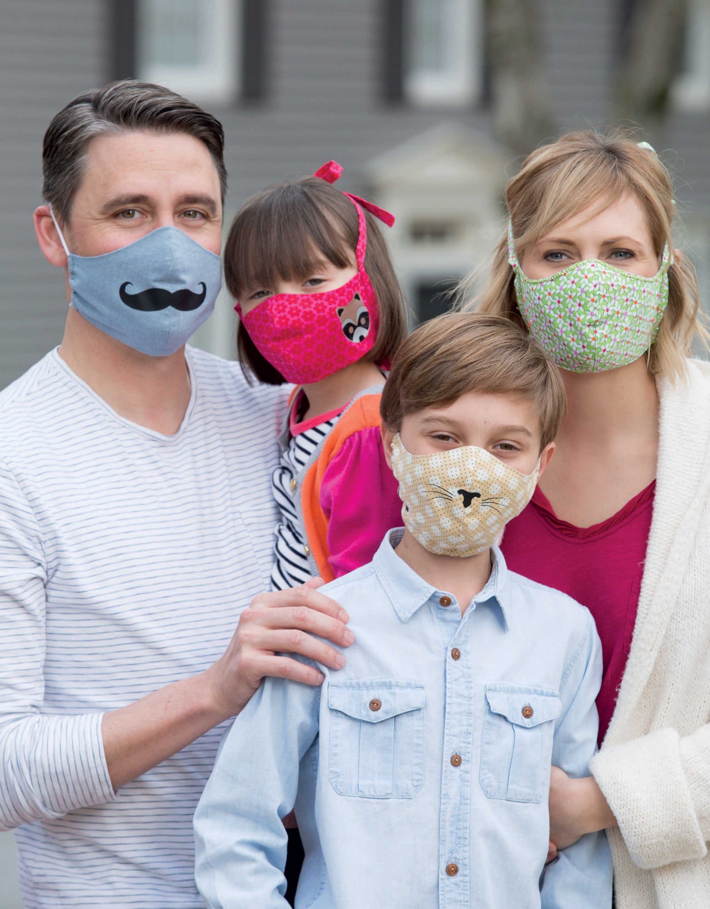 A family of four models colorful masks made with Breathe Easy—8 Simple Sew and Applique Particle Mask and Cap Projects by Leisure Arts, featuring fun, unique designs ideal for creative beginner sewing projects.