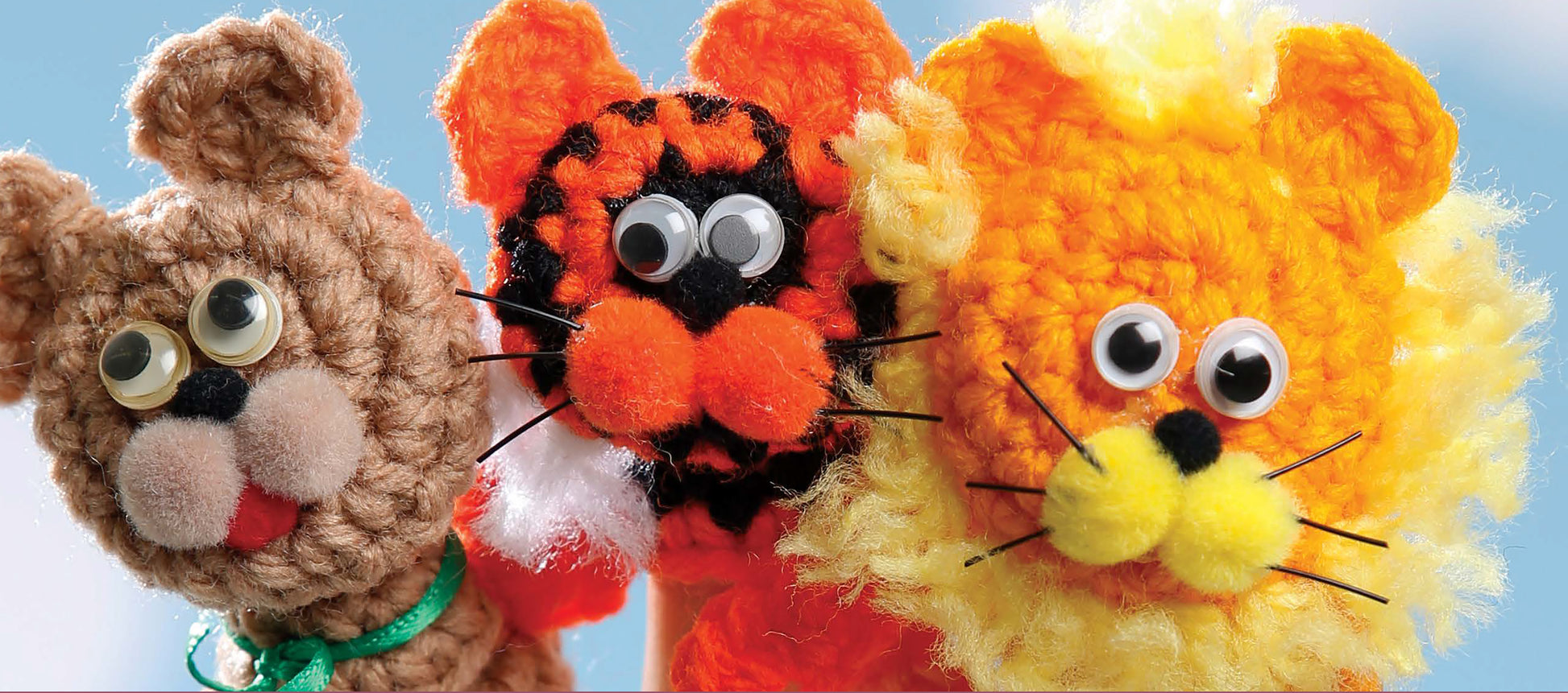 Finger Puppets At The Zoo by Leisure Arts features three crocheted animal puppets—a brown bear, orange tiger, and yellow lion—with googly eyes and pom-pom noses. Ideal for zoo animal or beginner crochet projects.