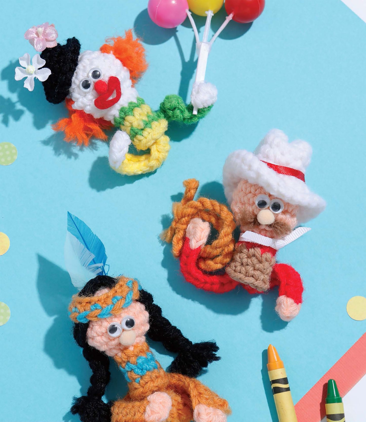 Three cute yarn finger puppets from Leisure Arts' "Finger Puppets Celebration" set: a clown with orange hair and balloons, a cowboy with rope and hat, and a Native American-inspired doll. Perfect for tiny town crochet fans or beginner crafters.