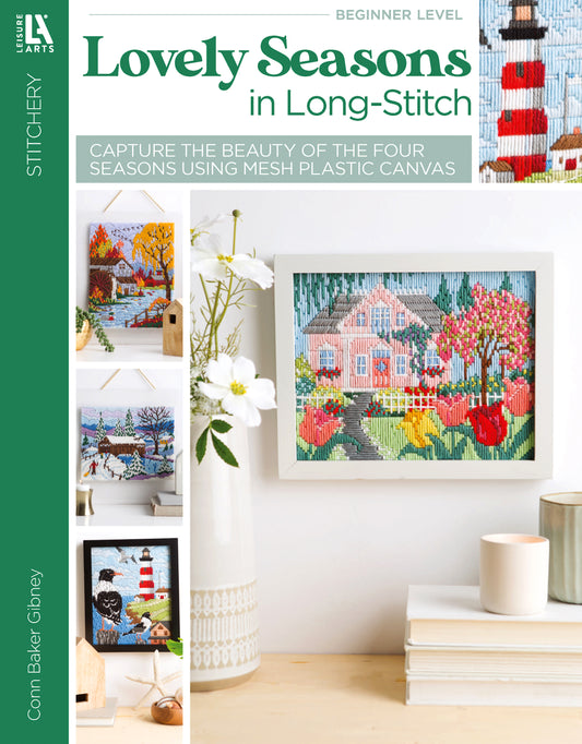 The “Lovely Seasons in Long-Stitch” book by Leisure Arts features long stitch designs of seasonal houses and landscapes, framed in white. The cover shows a pink house among autumn trees—ideal inspiration for plastic canvas projects.