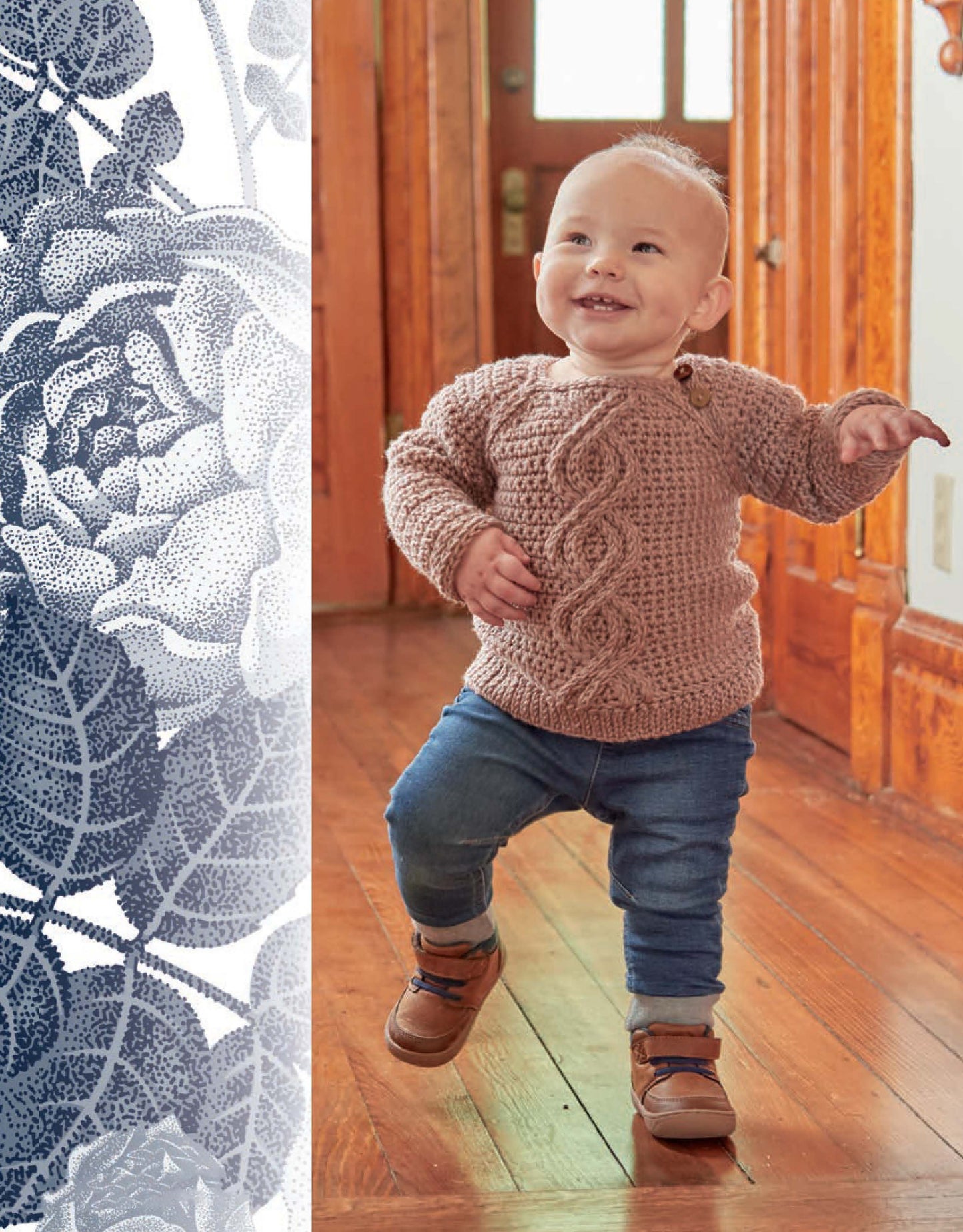 A smiling toddler wears a hand-crocheted brown sweater from the Vintage Baby Crochet collection by Leisure Arts, blue jeans, and brown shoes while walking on a sunlit wooden floor. A floral pattern appears at the left of the image.