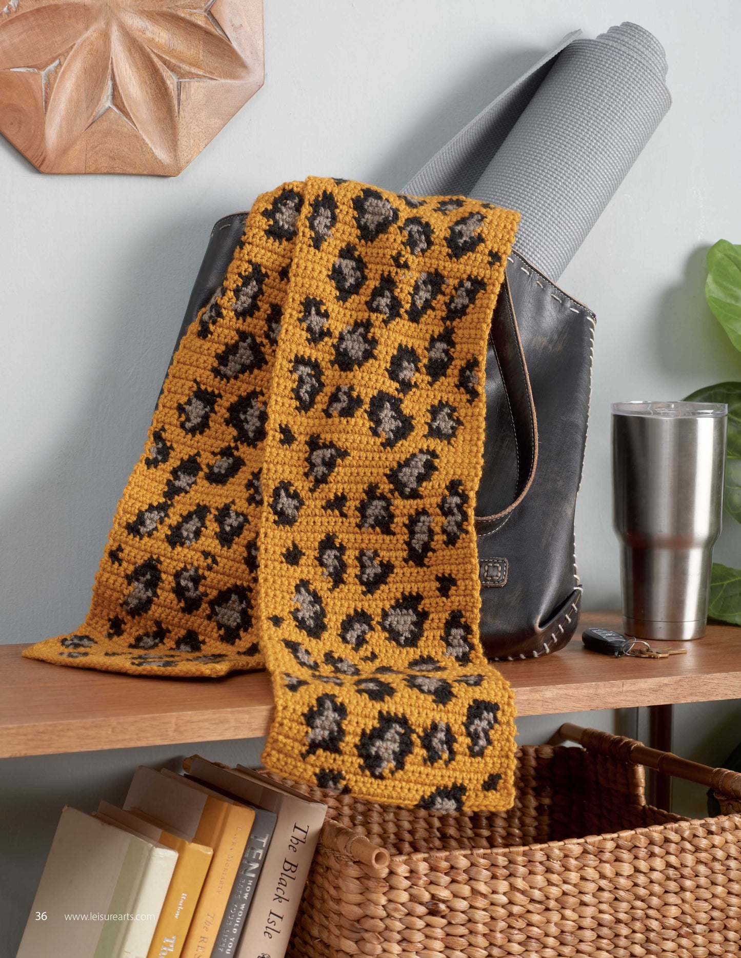 Animal Prints—10 Designs to Add a Little Wildlife to Your Wardrobe and Home Decor by Leisure Arts features a crocheted yellow and black animal print scarf on a leather bag, with yoga mat, tumbler, books, and basket—perfect for beginner projects.