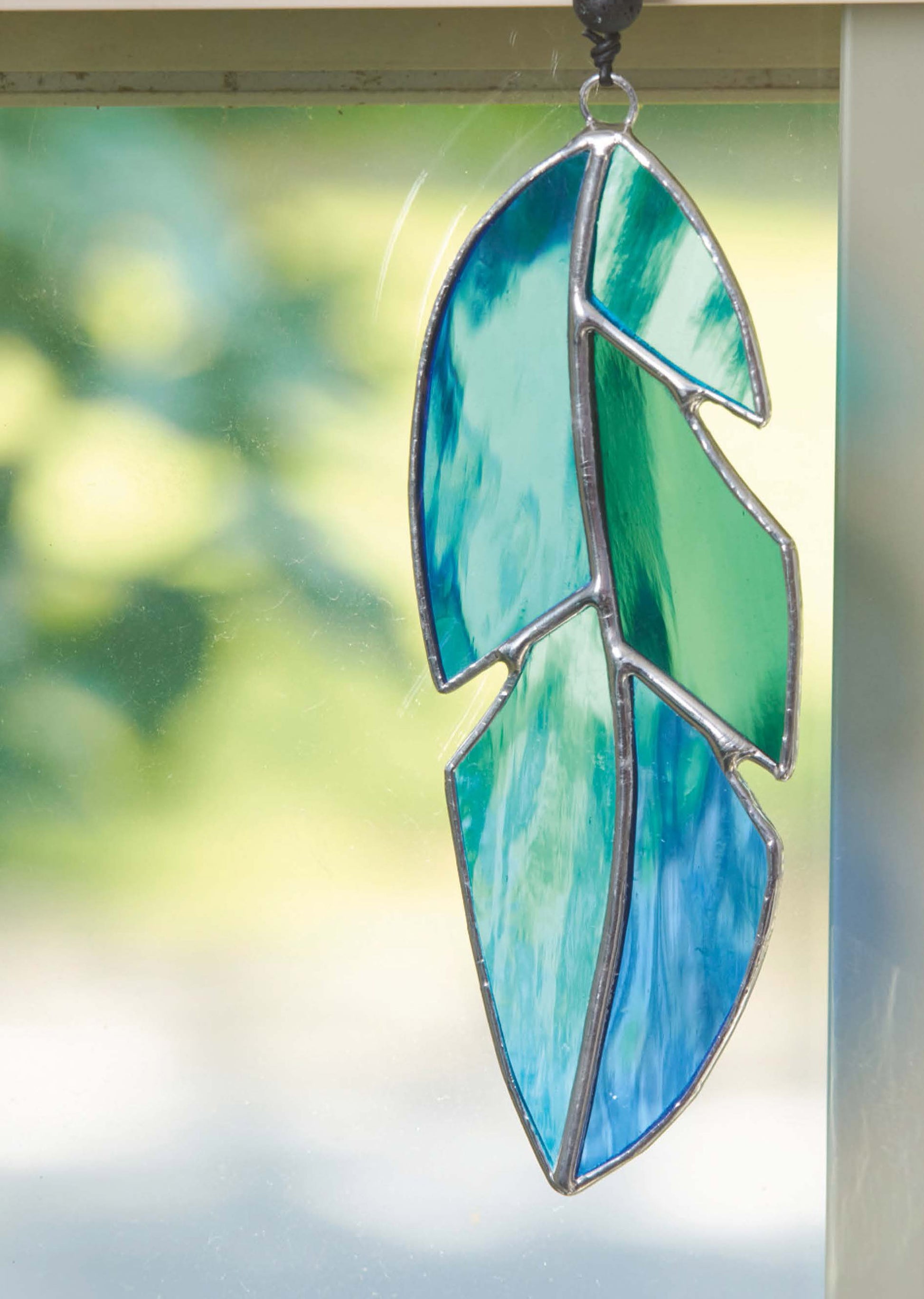 The Stained Glass for Beginners Digital Download by Leisure Arts features a blue and green feather ornament—a great starter project for anyone eager to try beautiful glass art.