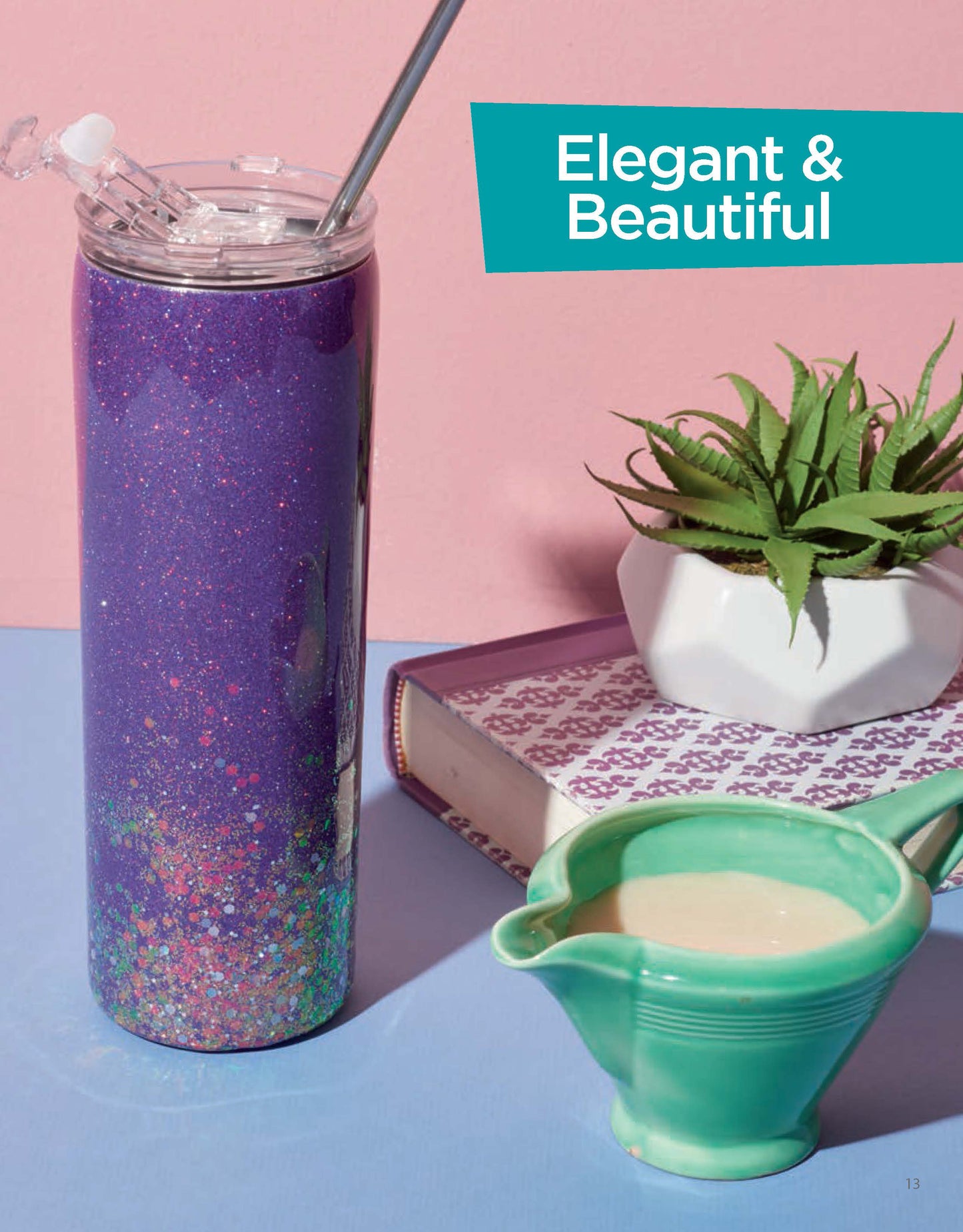 A tall, glittery purple tumbler made using Leisure Arts’ Resin Tumbler Designs Digital Download sits on a blue surface next to a green cream pitcher, a beginner book, a small potted succulent, and an Elegant & Beautiful sign.