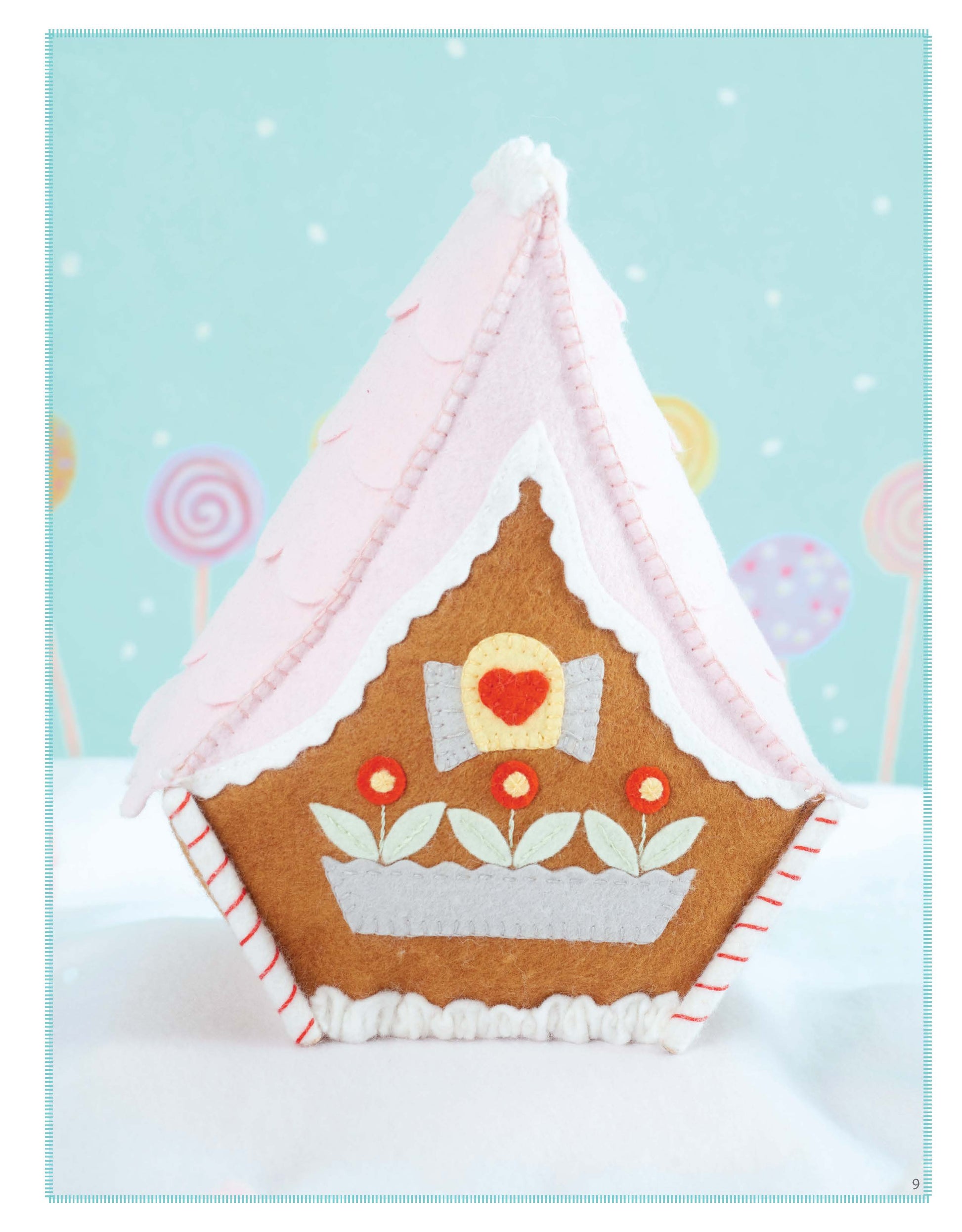 The Leisure Arts Gingerbread House features a pink roof, white icing trim, and felt decorations like red flowers and a heart—ideal inspiration for wool felt crafts or beginner embroidery—shown on a pastel background with lollipop designs.