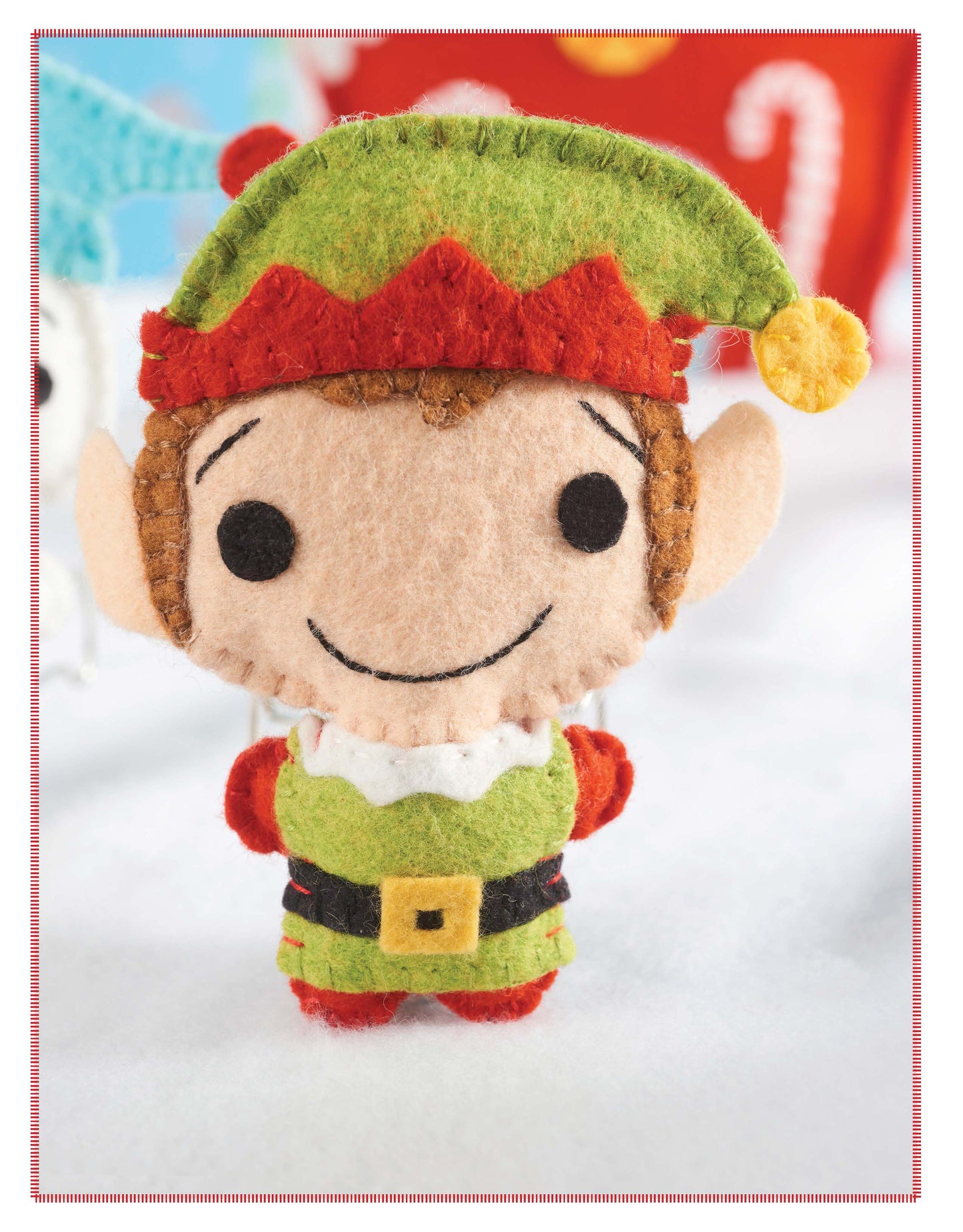 Santa's Workshop by Leisure Arts features a plush felt elf doll with a green hat, red and green outfit, and pointy ears—perfect for Christmas crafts or DIY holiday decorations. Festive décor creates a cheerful holiday backdrop.