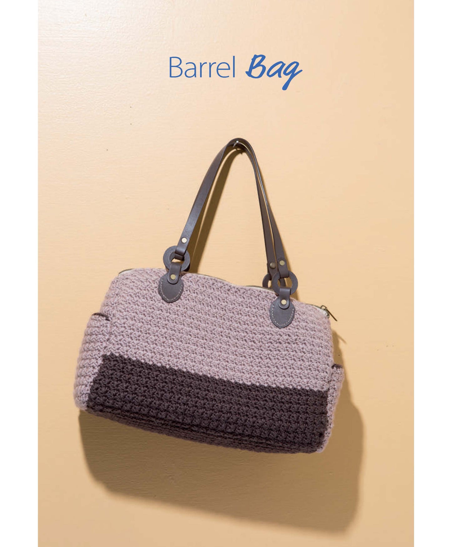 A beige wall displays Barrel Bag above a barrel-shaped crocheted handbag, featuring light beige and dark brown tones with dark handles. Pattern from Crochet Handcrafted Handbags Book 4 by Leisure Arts—perfect for crochet bag inspiration.