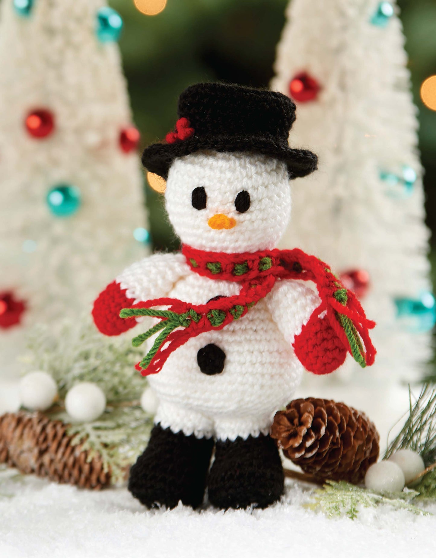 Christmas Friends by Leisure Arts features 4 adorable crochet Christmas characters, including a snowman with festive accessories. Perfect for holiday decor or beginner projects, and pairs beautifully with pinecones and white Christmas trees.