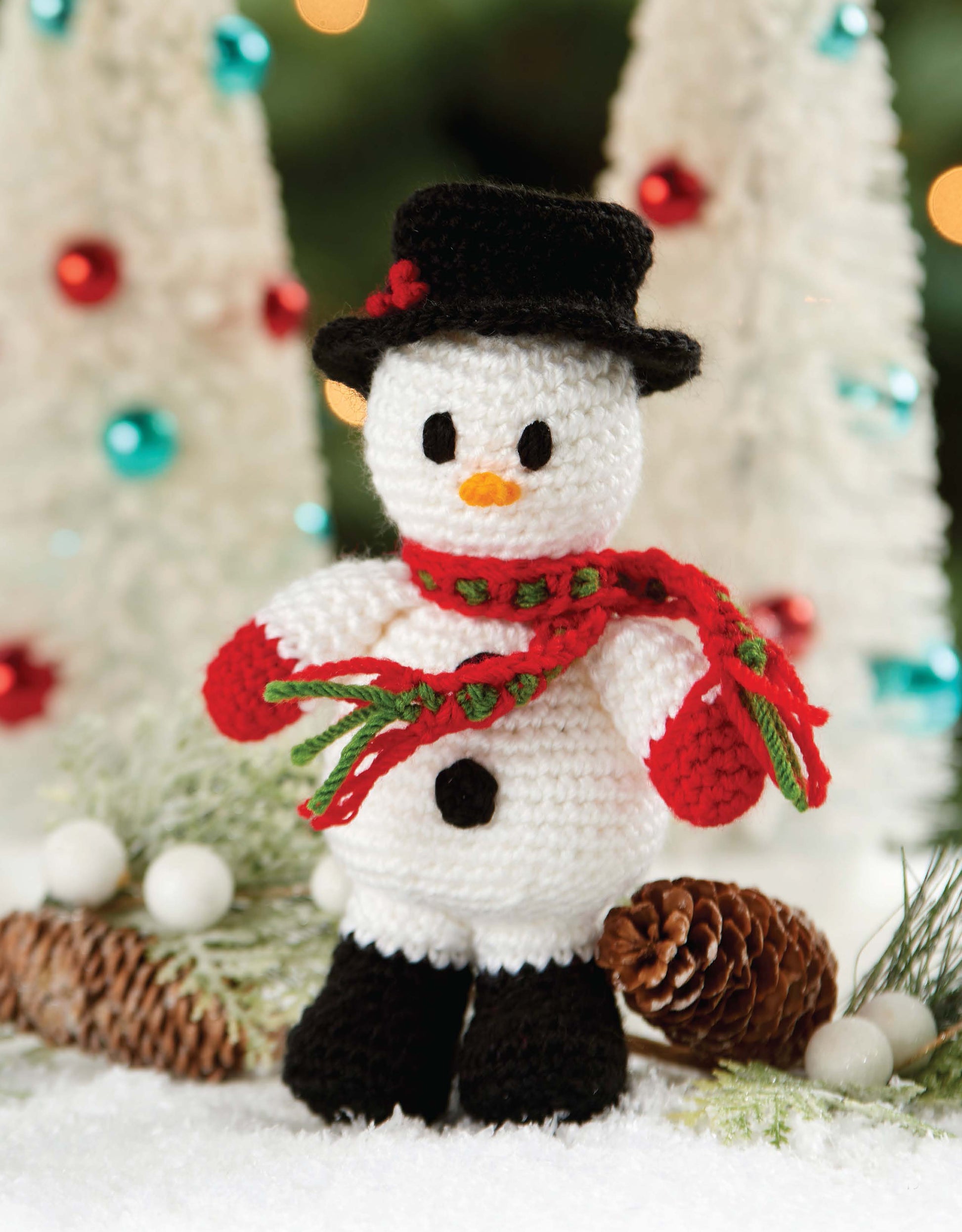 Christmas Friends by Leisure Arts features 4 adorable crochet Christmas characters, including a snowman with festive accessories. Perfect for holiday decor or beginner projects, and pairs beautifully with pinecones and white Christmas trees.